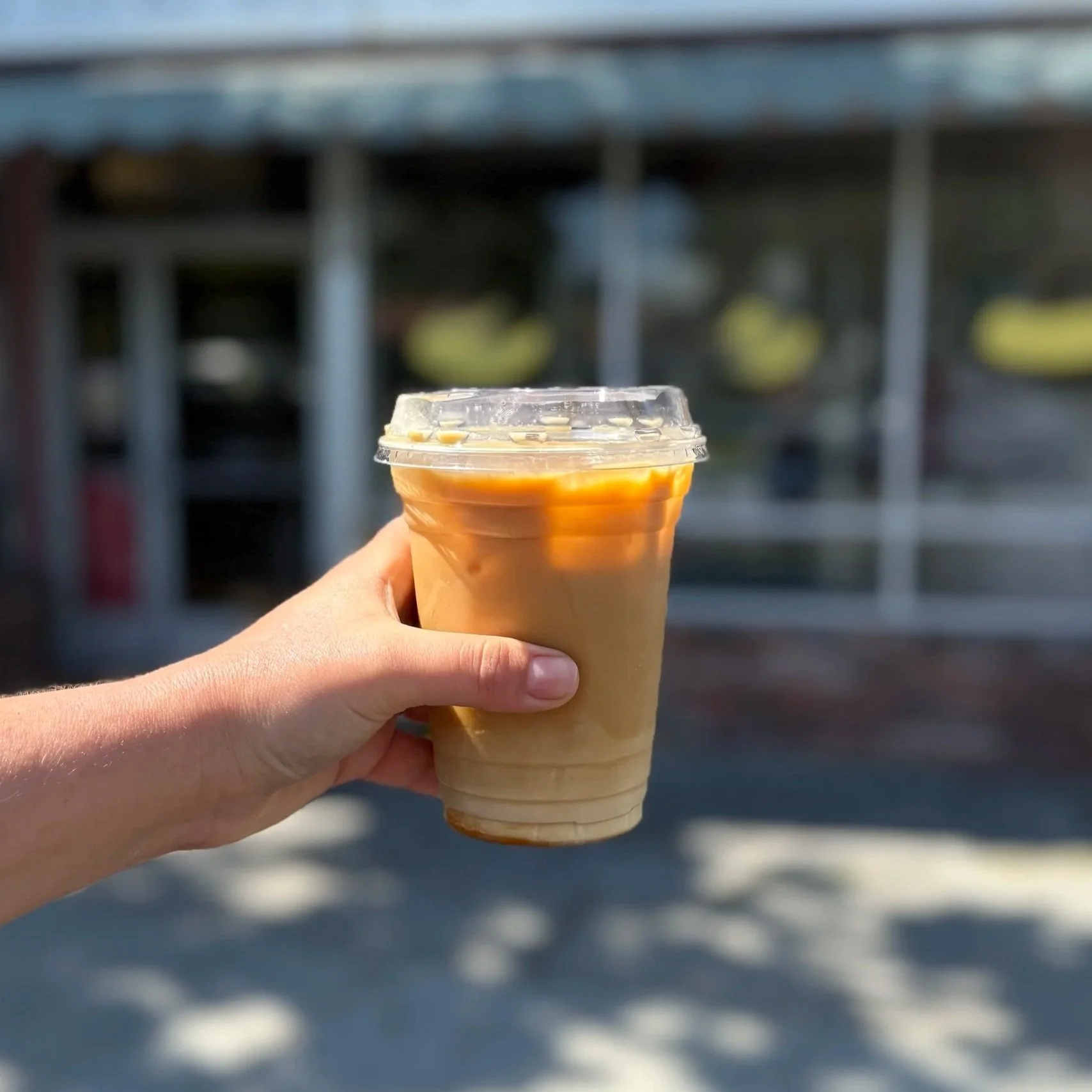 Strong iced coffee in front of As Kneaded Bakery's storefront.