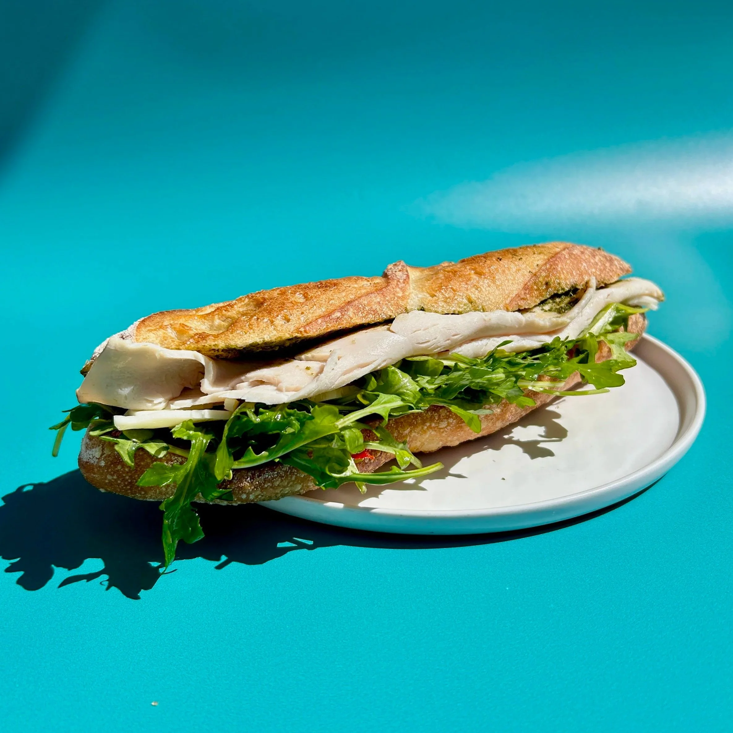Thick schmears of sundried tomato mayo and housemade AKB pesto go with sliced turkey, provolone cheese, and peppery arugula. All on our demi baguette.