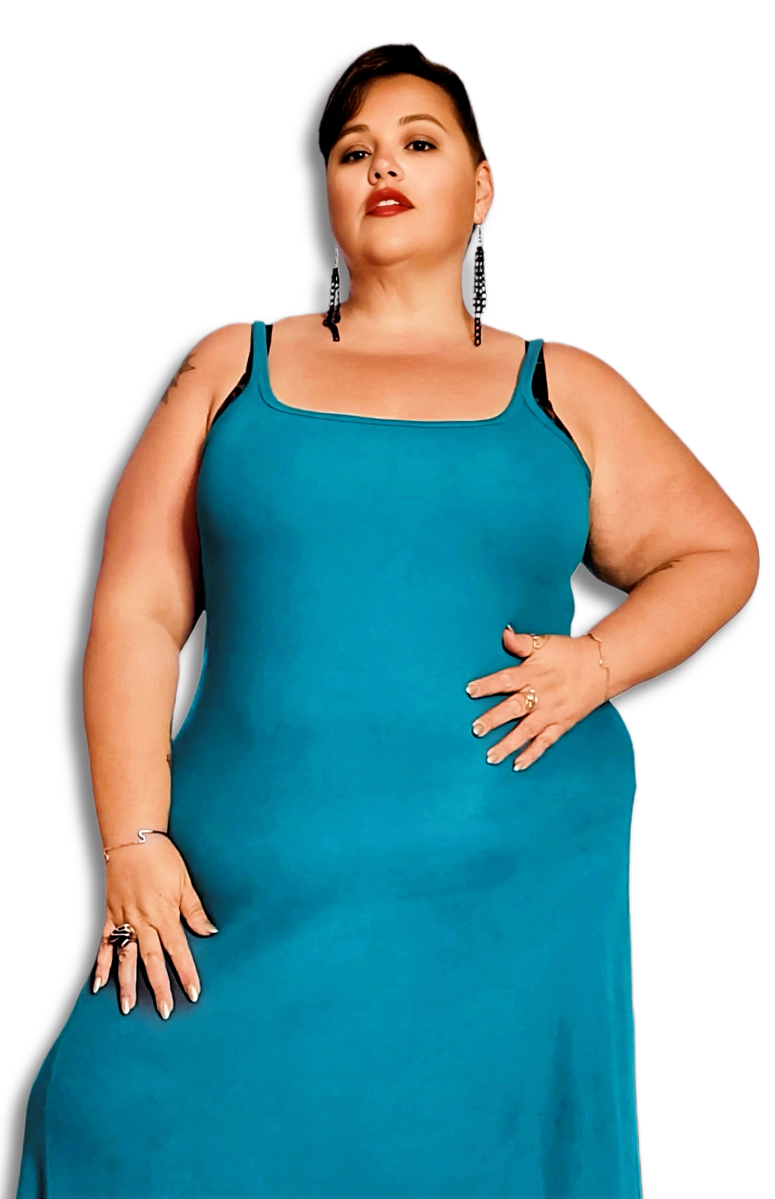 Toronto BBW provider Lush Lynn standing confidently against a black background, wearing a teal sleeveless dress with black straps, large earrings, and multiple rings and bracelets.