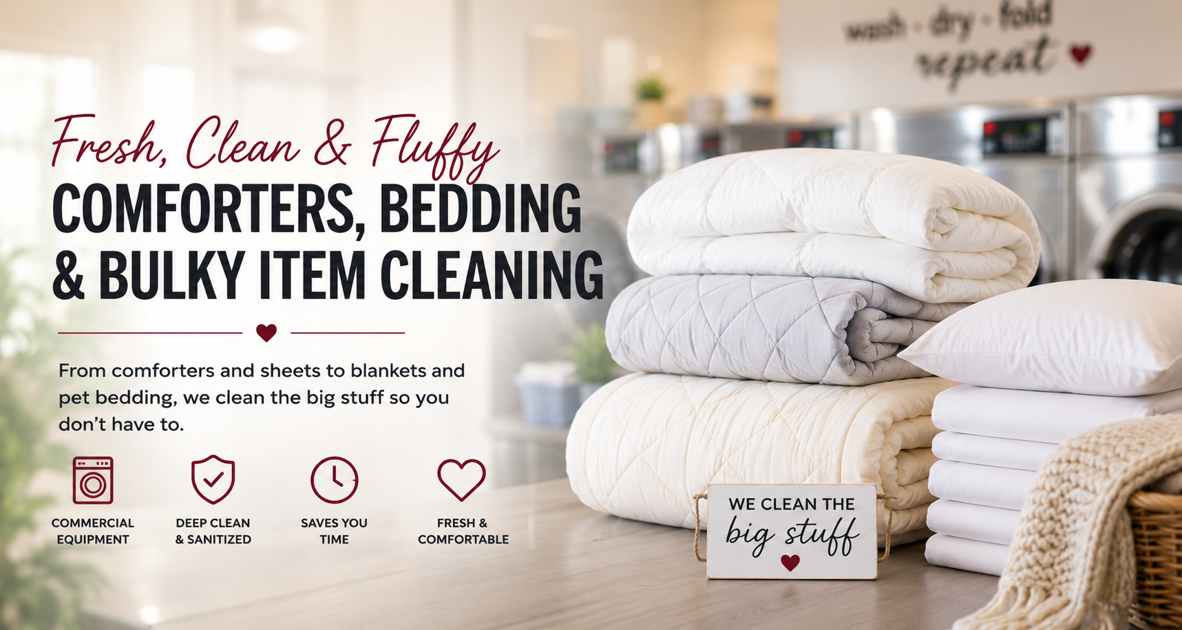 Stacked blankets and pillows on a table with a sign that reads, 'We clean the big stuff,' in a laundry or cleaning service setting.