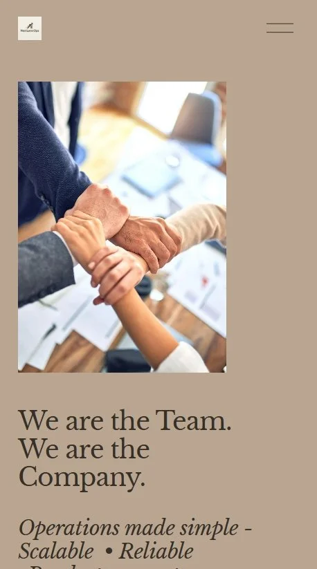 Close-up of diverse team members' hands stacked together on a table, with documents and a laptop in the background, symbolizing teamwork.