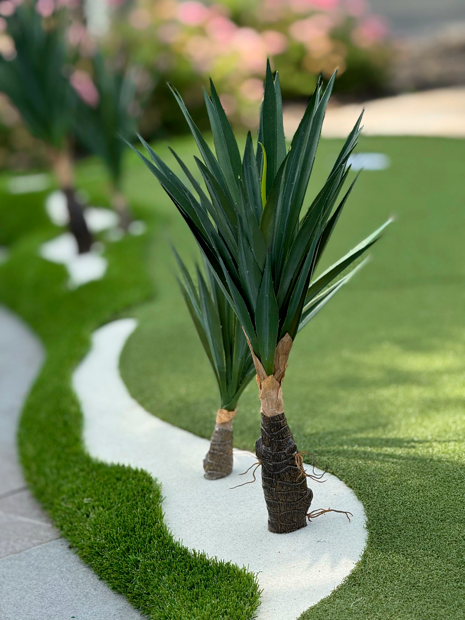 close up picture of artifical tropic palm trees that sit ontop of an artificial grass modular putting green