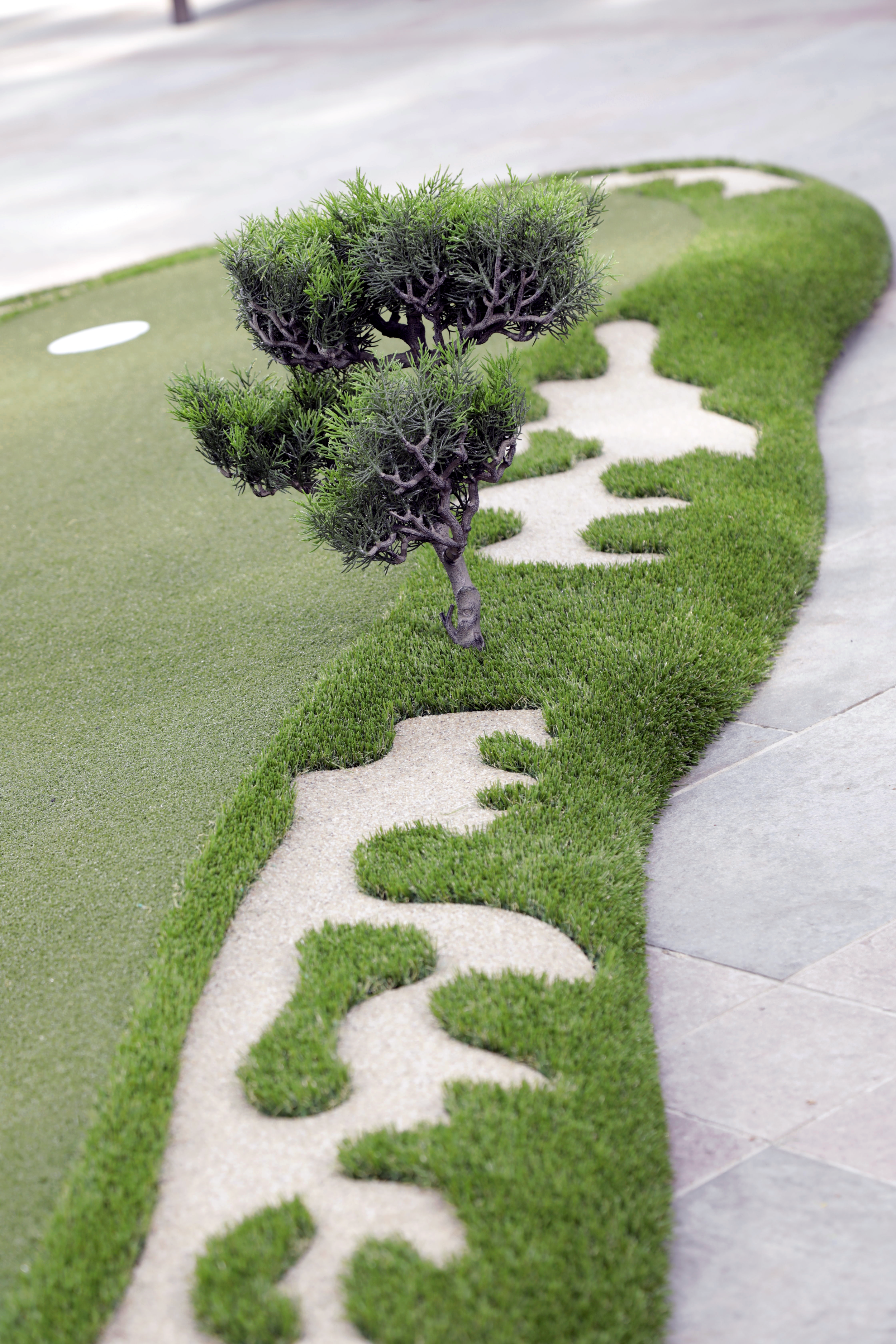 close up of a fake tree on the side of an artificial grass modular putting green