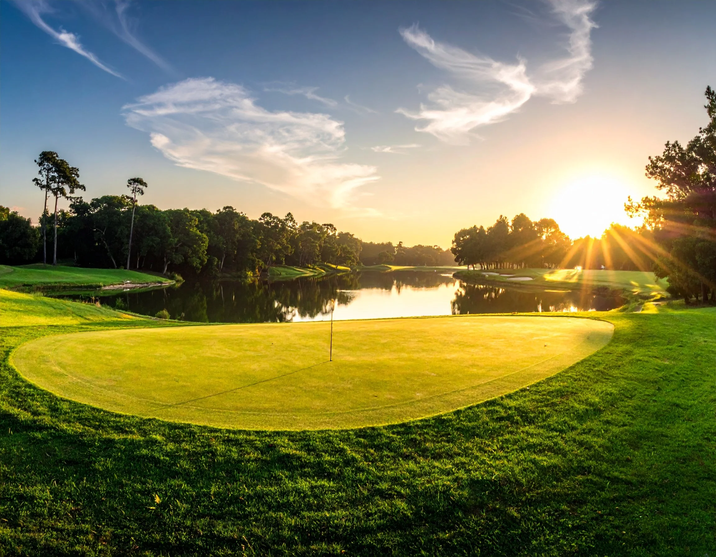 golf course green at sunset with pond in the background