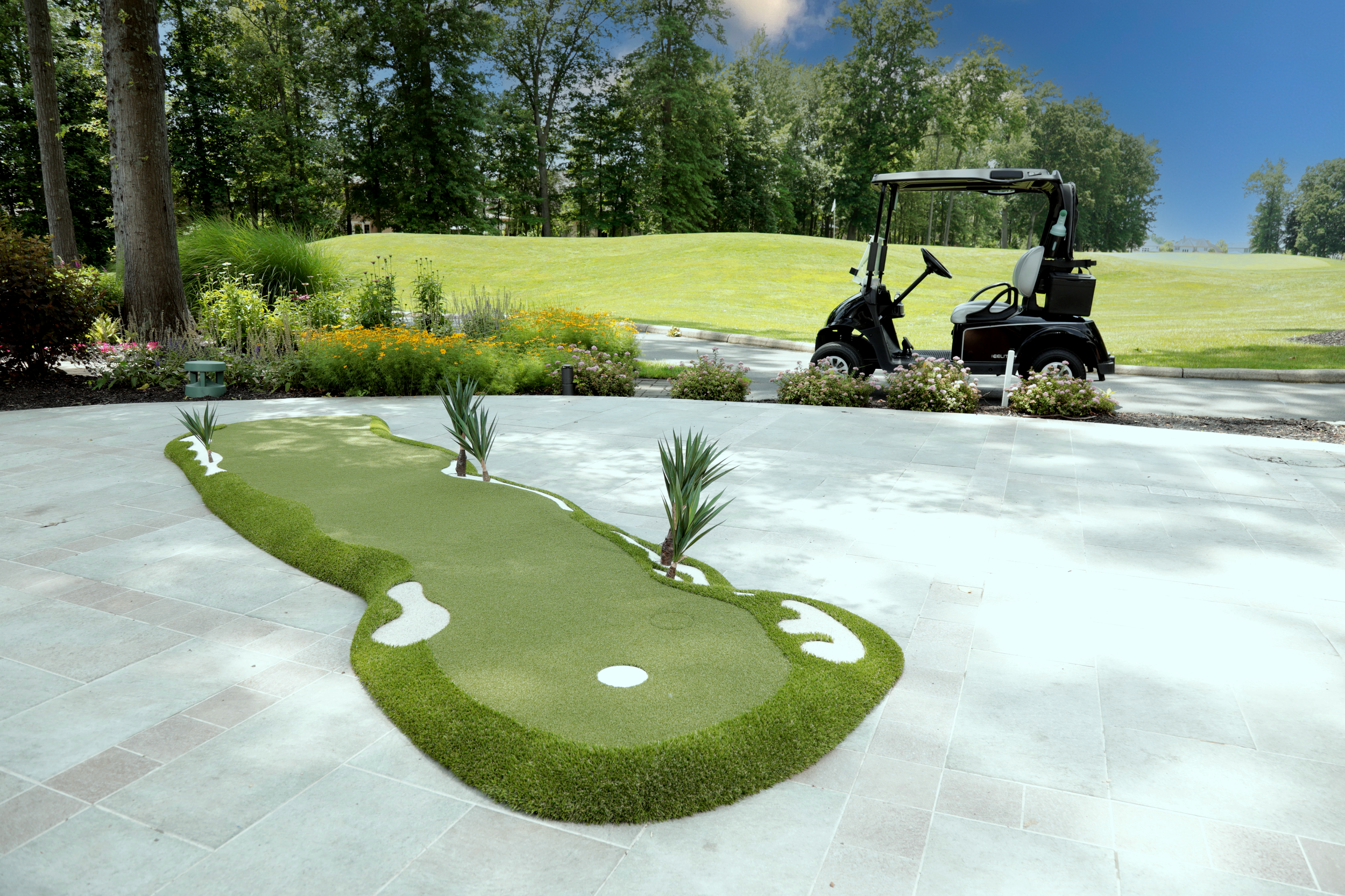 Portable putting green on patio with golf cart, trees and golf course in background