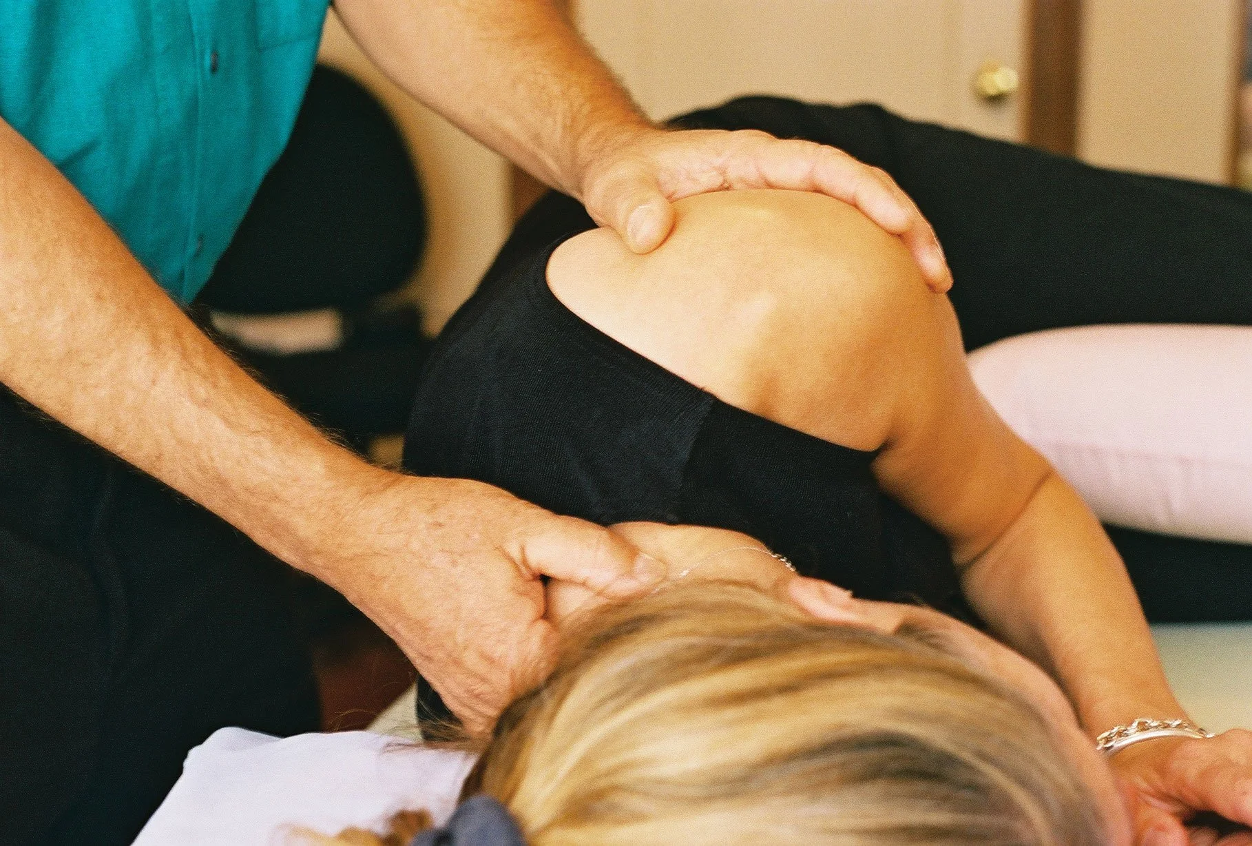 A person receiving a knee massage while lying on a massage table.