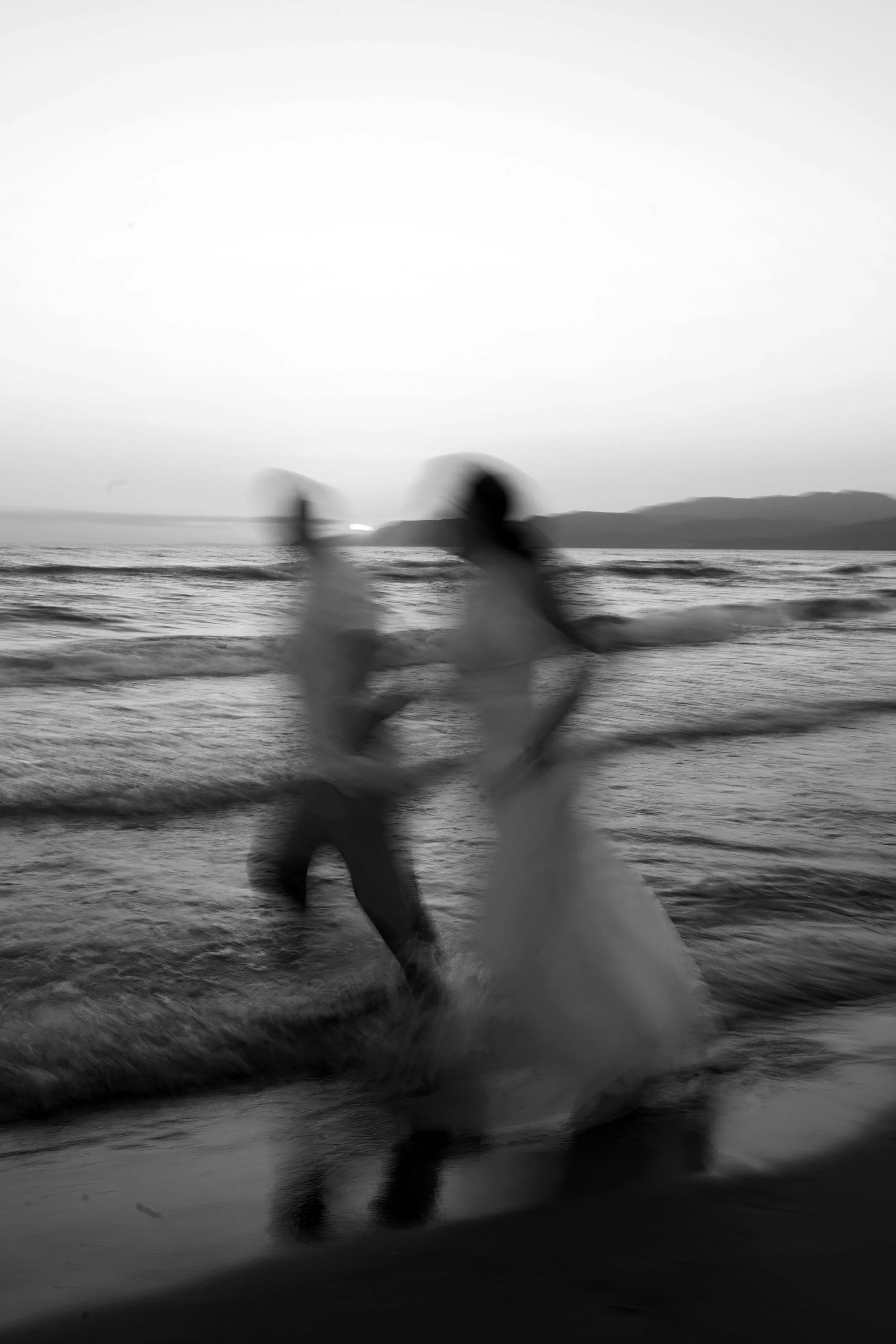 Due persone che ballano sulla spiaggia al tramonto, l'immagine è sfocata e in bianco e nero.