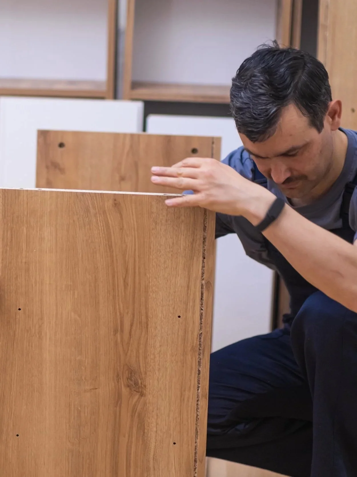 Man inspecting a wooden panel in a woodworking workshop.