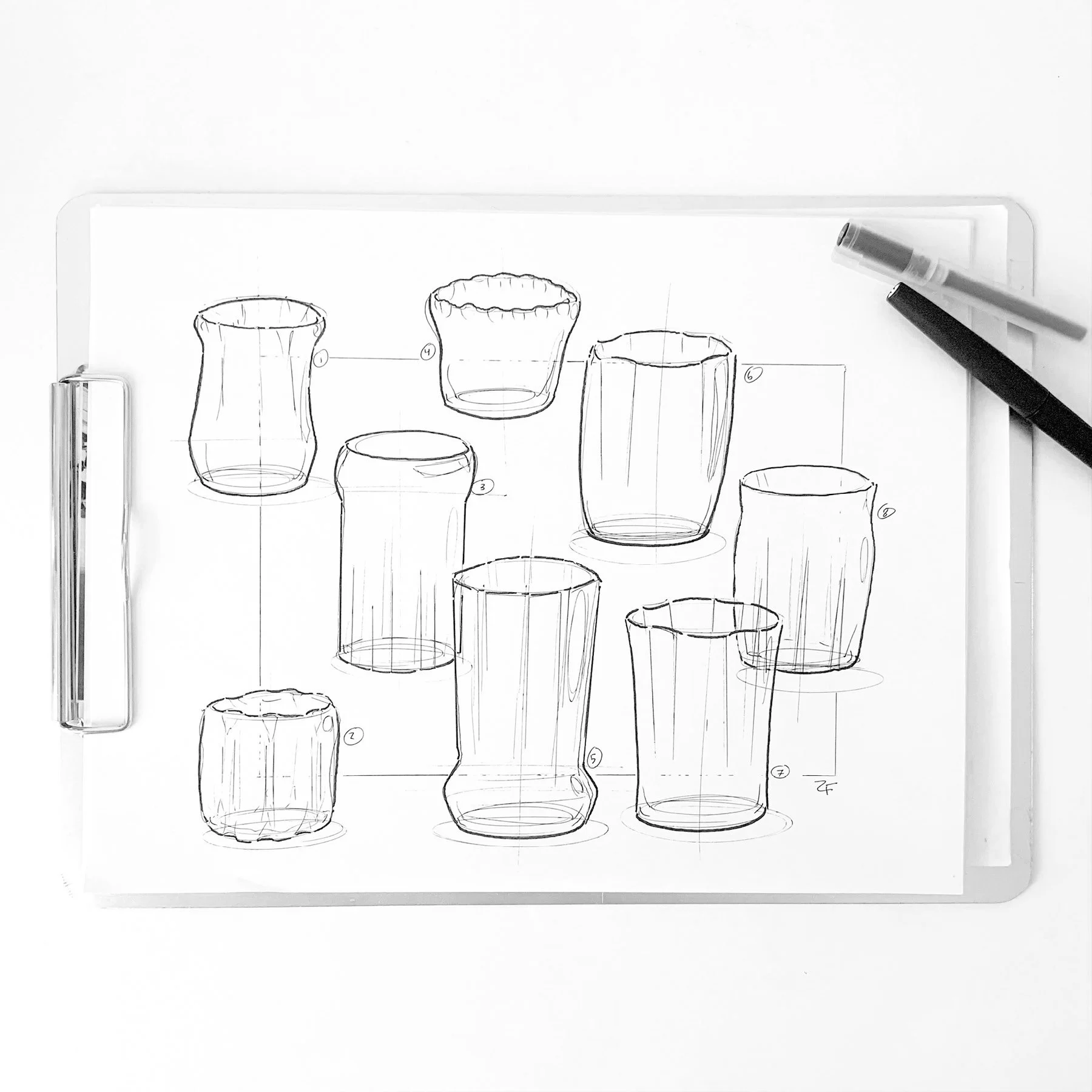 Sketch of various glassware and vases on a sheet of paper, with two markers resting on the top right corner.