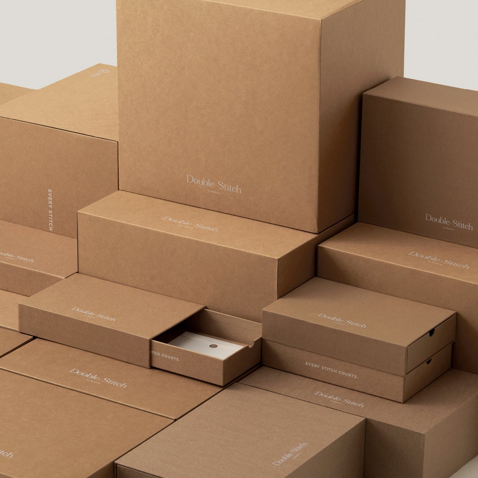 Multiple brown cardboard boxes labeled 'Double Stitch' and 'Every Stitch Counts' stacked together.
