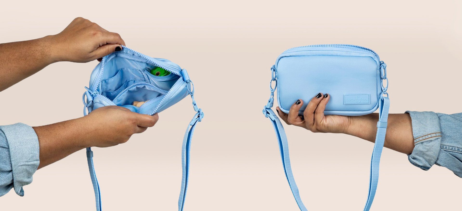 Two hands holding blue bags, with the one on the left showing the open interior containing small items and the one on the right holding the closed bag.  Lucy & Co. Crossbody treat bag.
