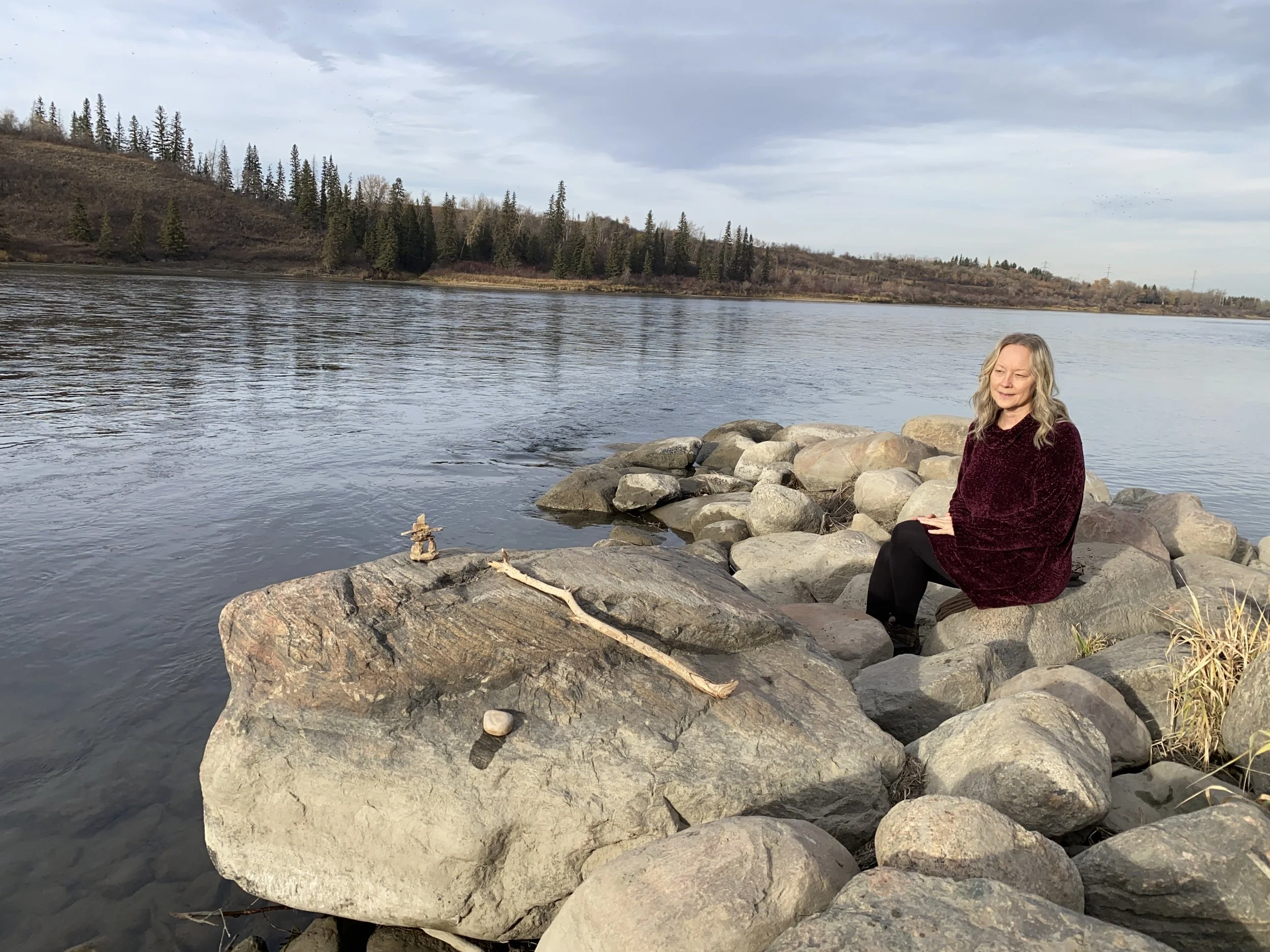 Dr. Sylvia Peske honouring a symbolic alter by the river representing grounding, clarity, direction, and the natural rhythm of transformation.