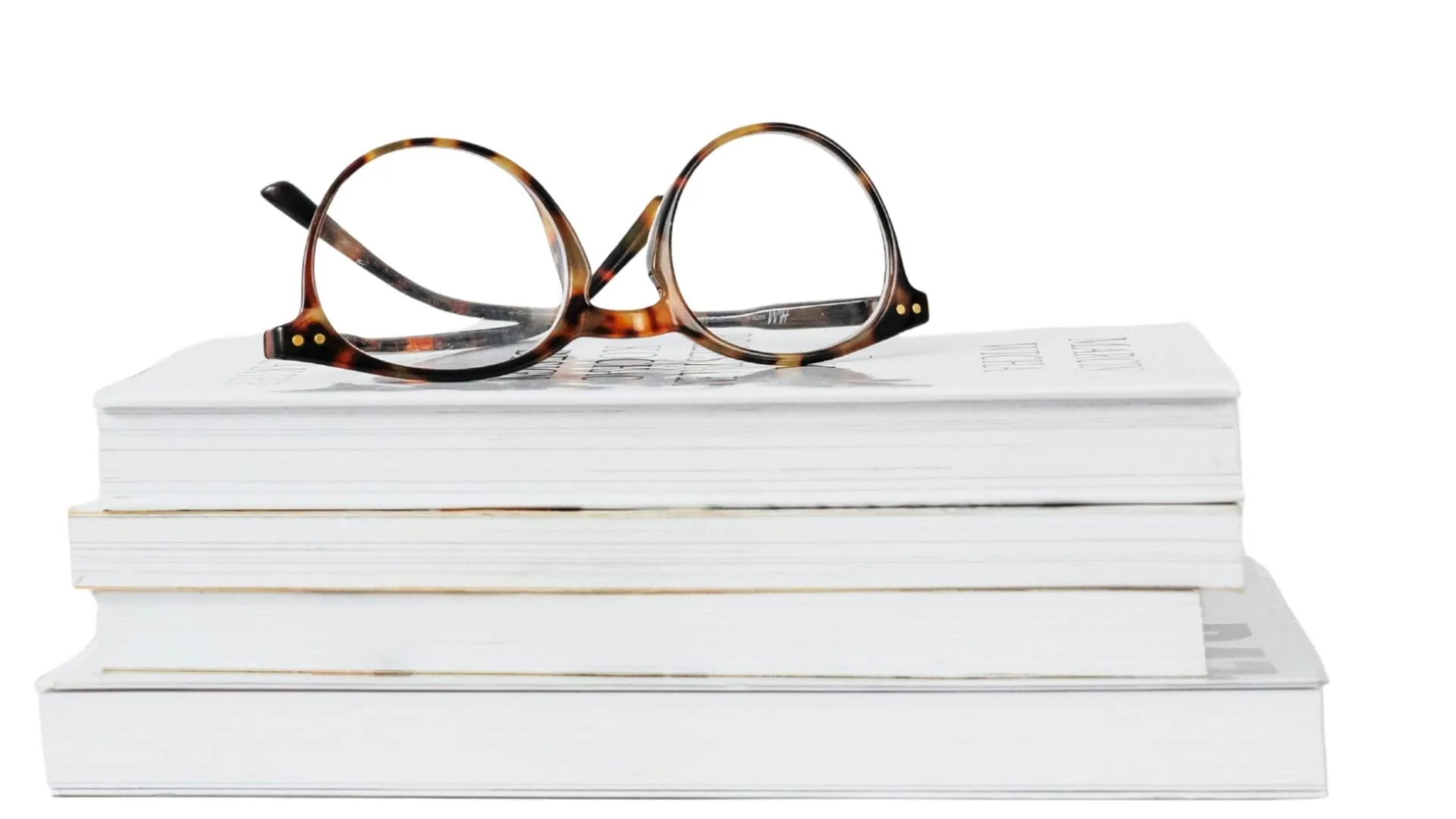 Three stacked white books with a pair of tortoiseshell eyeglasses resting on top, against a white background.