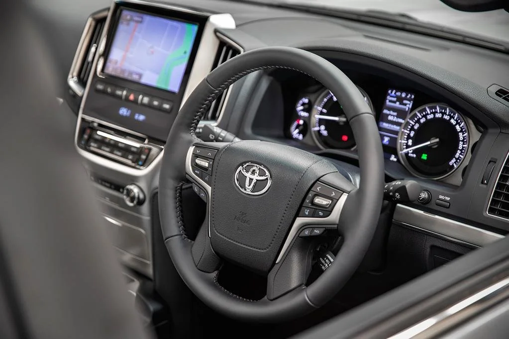 Interior of a Toyota vehicle showing a steering wheel, digital dashboard, and a built-in GPS navigation screen.