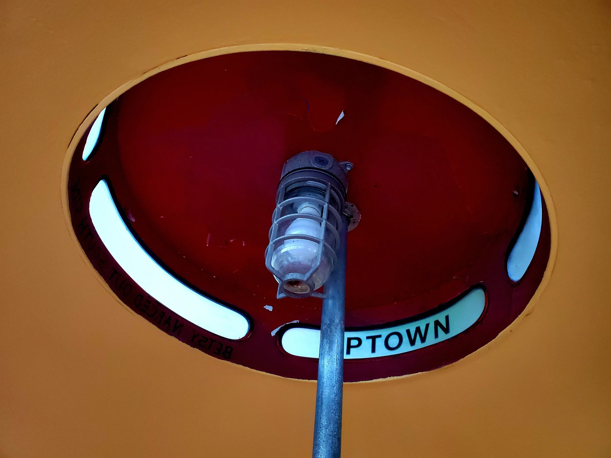 Fire alarm pull station with a red background and white label that says 'BETHESDA' and other text.
