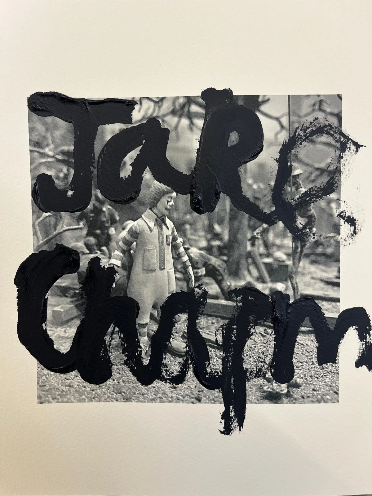 Black paintbrush strokes spell out "Joke" over a black and white photograph of a young girl standing outdoors in a park or yard with trees and other children in the background.