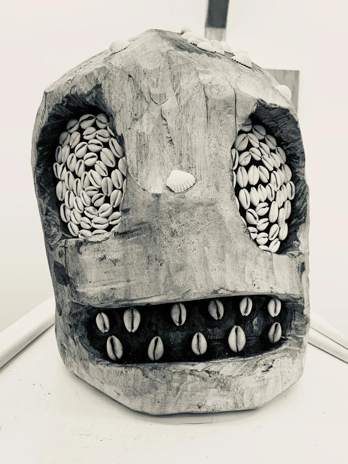 A carved wooden skull filled with seashells to resemble the skull's eyes and mouth.