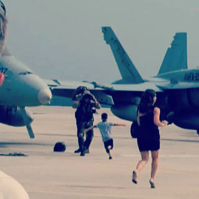 People running near military aircraft on tarmac