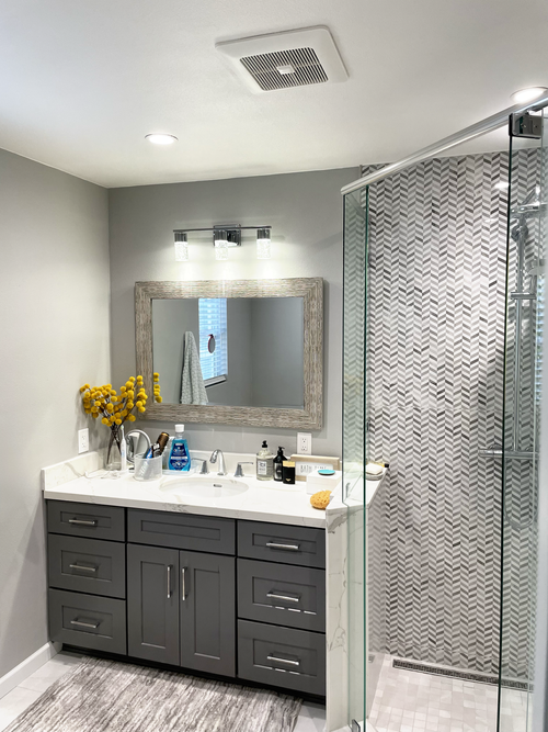 Bathroom with herringbone tile shower and gray vanity