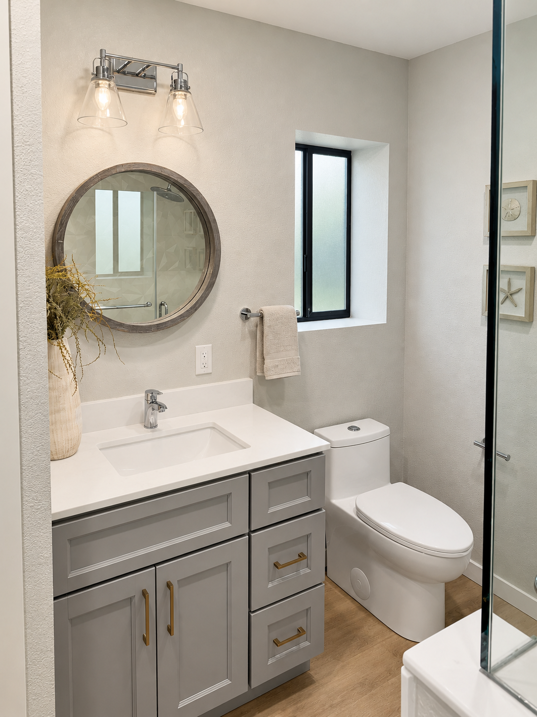 Gray shaker vanity with brass handles, a white countertop and a round mirror, bathroom remodel in Cupertino, CA