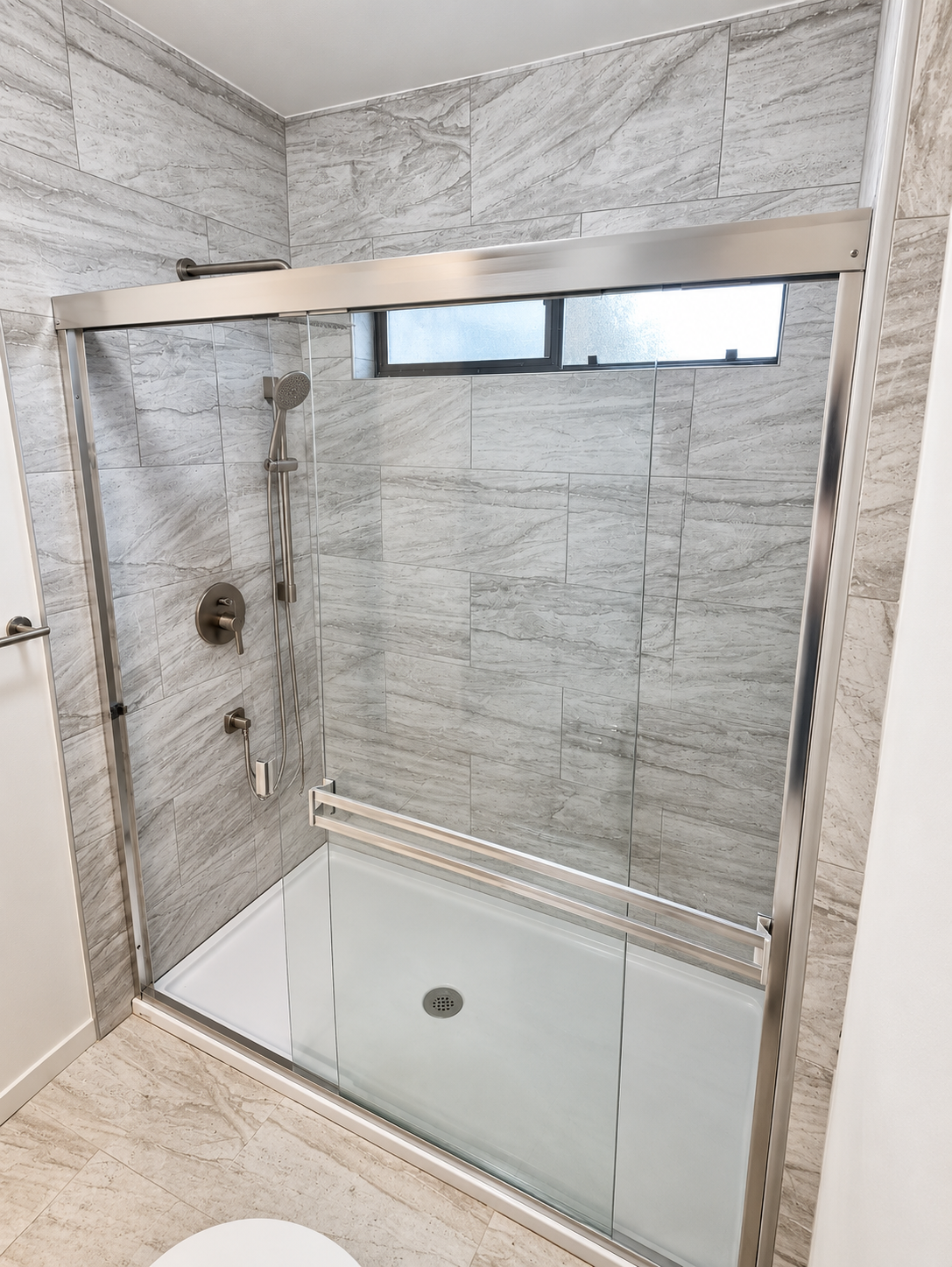 Walk-in shower with gray stone-look tile and sliding glass doors, bathroom remodel in Santa Clara, CA