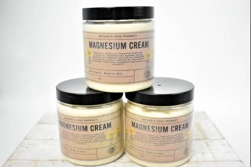 Three jars of magnesium cream stacked on a white surface with a plain white background.
