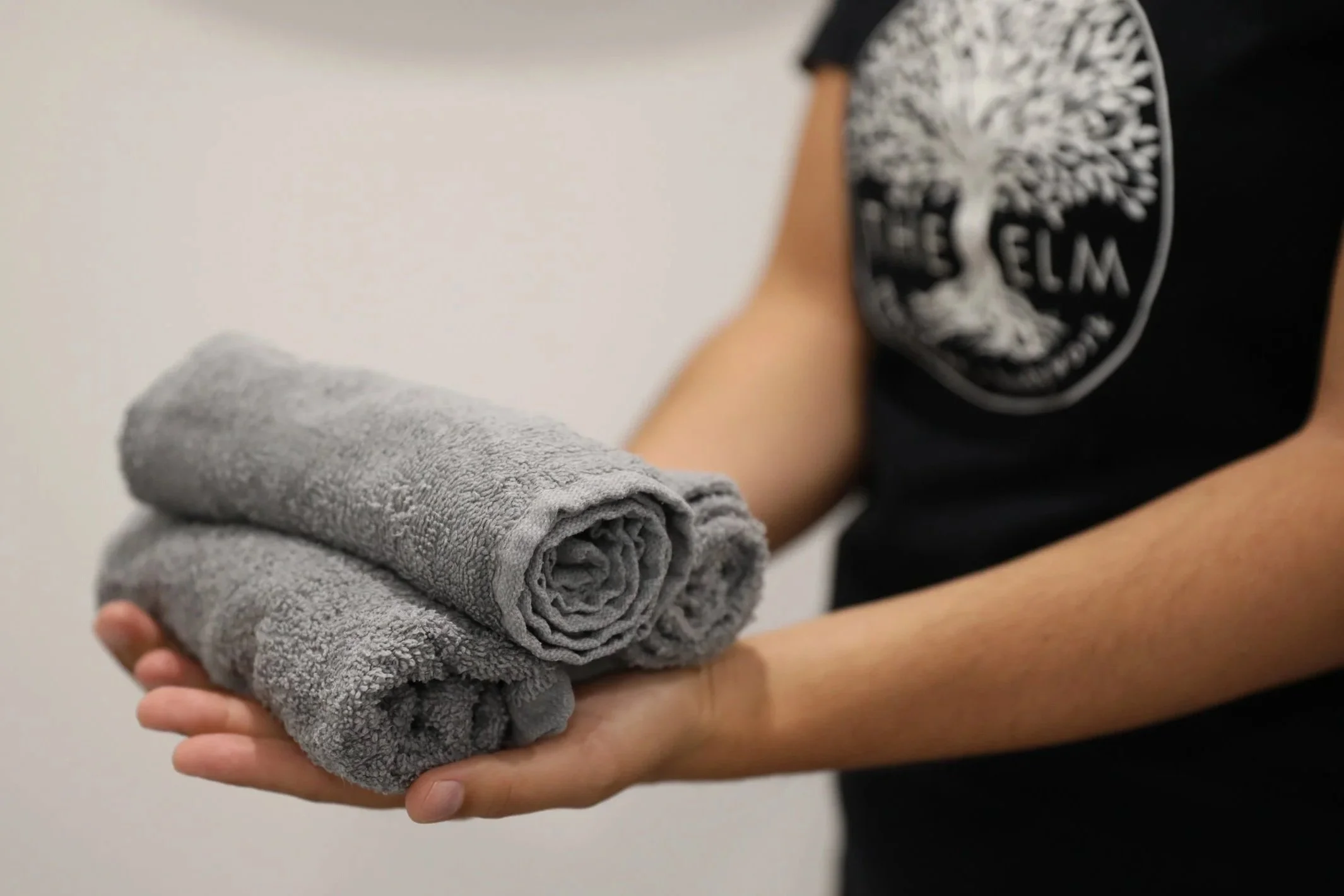 Person holding two folded gray towels.