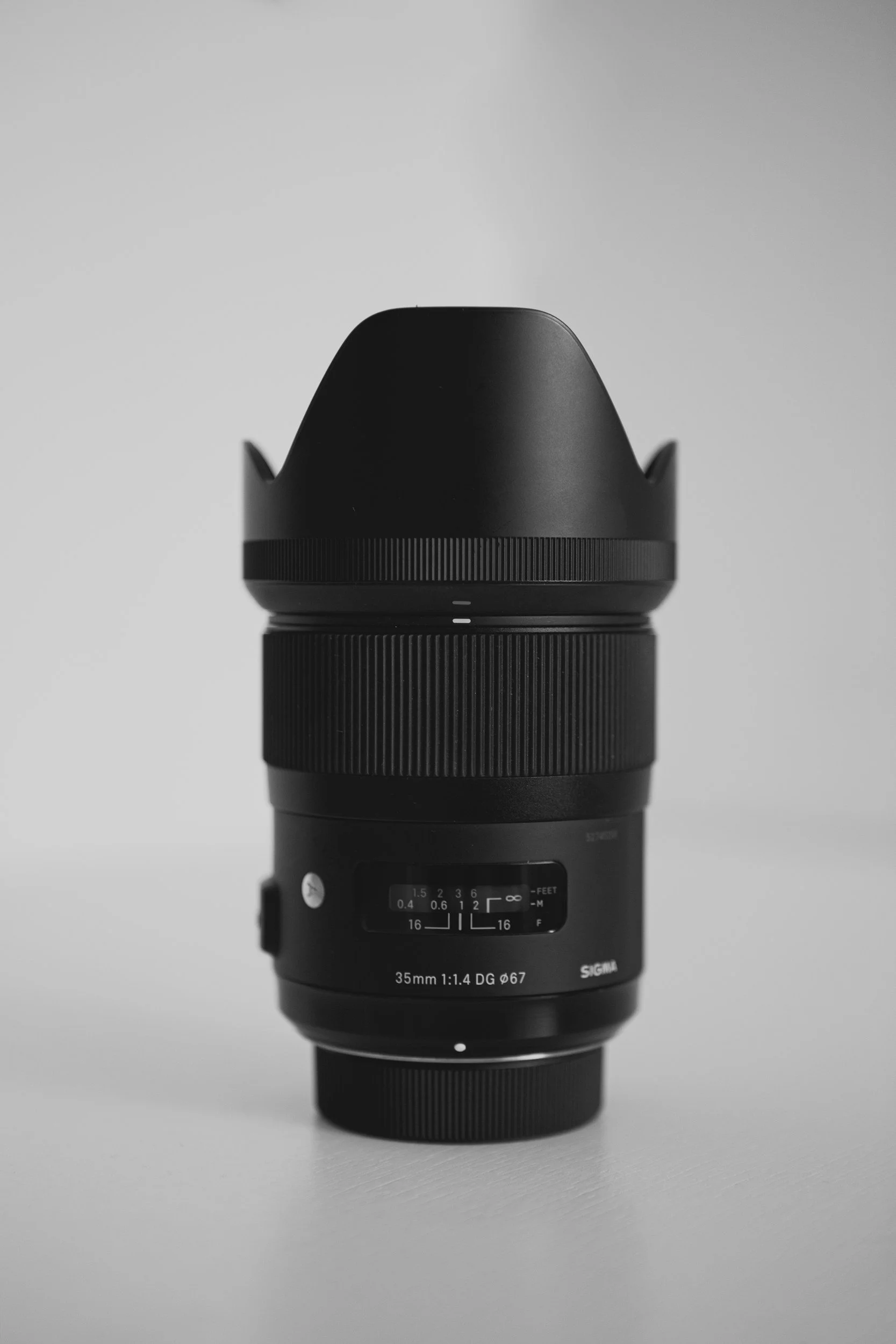 Camera lens stood upright on table with lens hood attached.