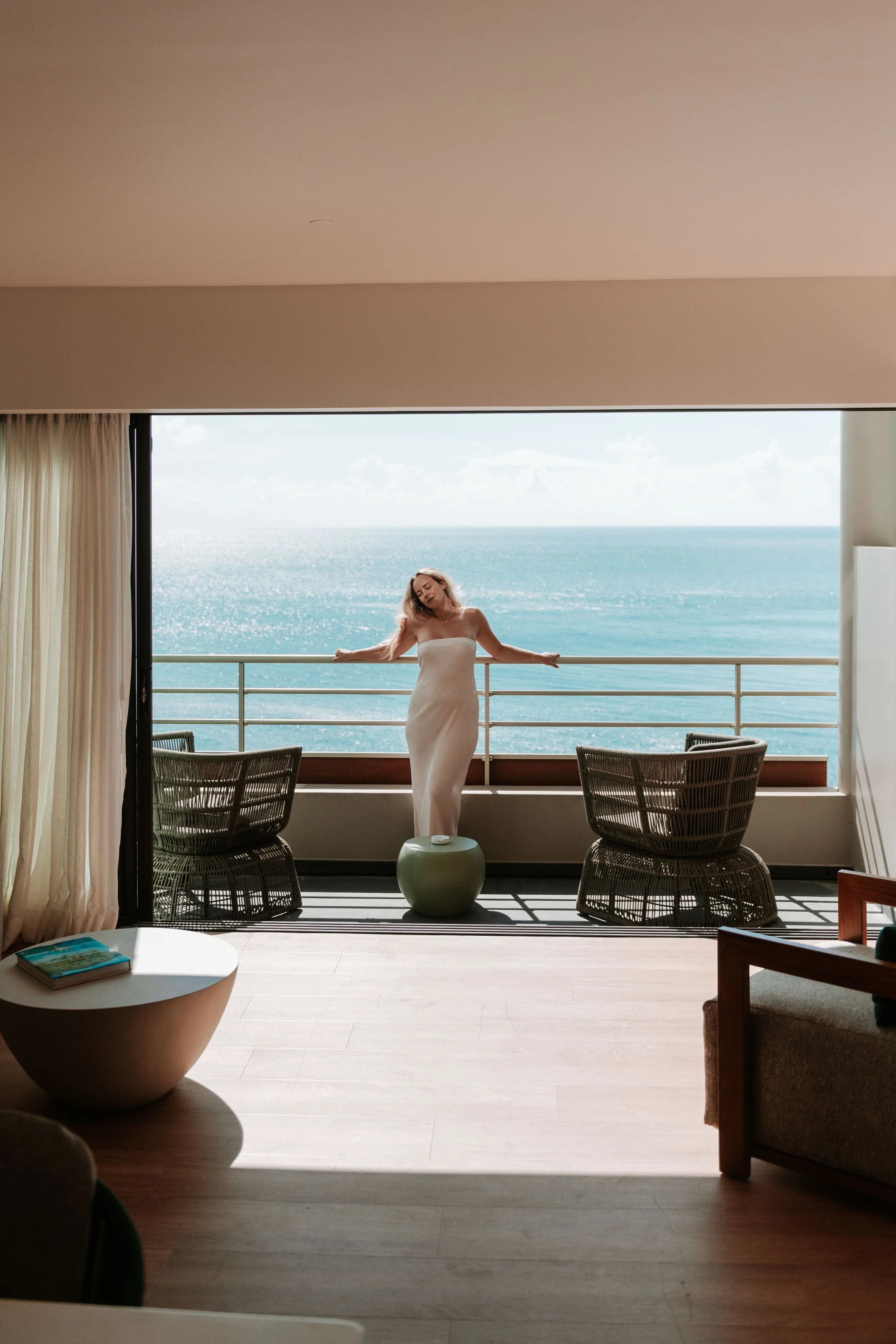 Femme en robe longue blanche sur un balcon avec vue sur la mer
