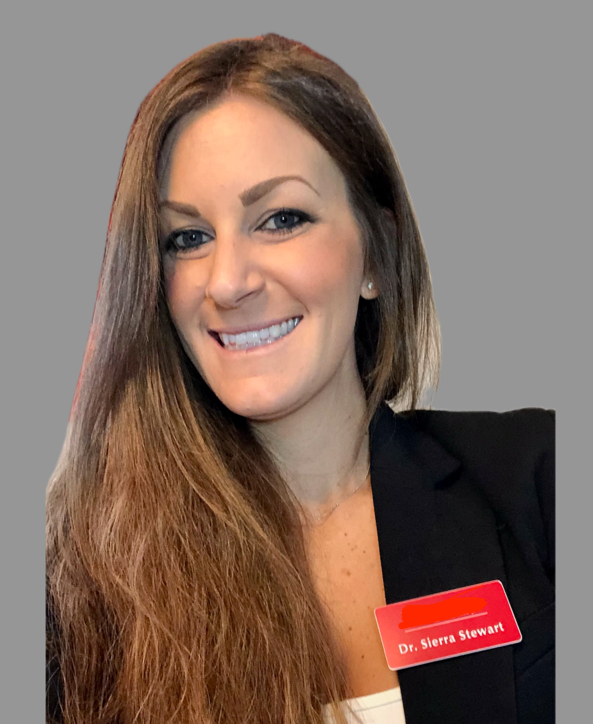A woman with long brown hair and light skin, smiling, wearing a black blazer and a red name tag that reads 'Dr. Sierra Stewart' against a plain gray background.
