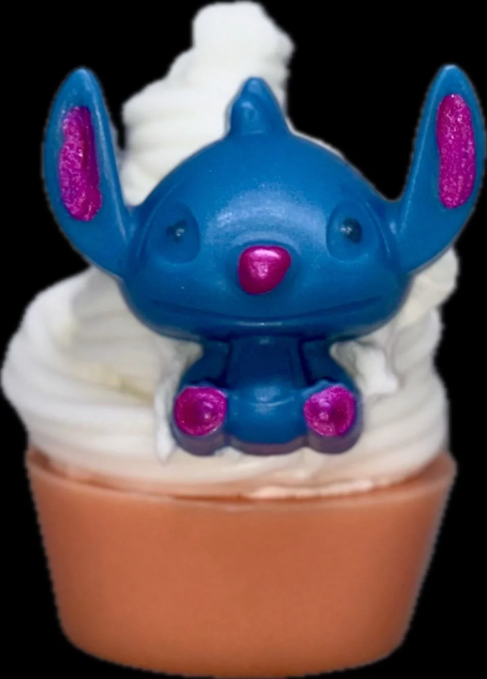 Blue cartoon character sitting on white frosting in a cupcake liner, featuring pink inner ears and paws against a plain light background.