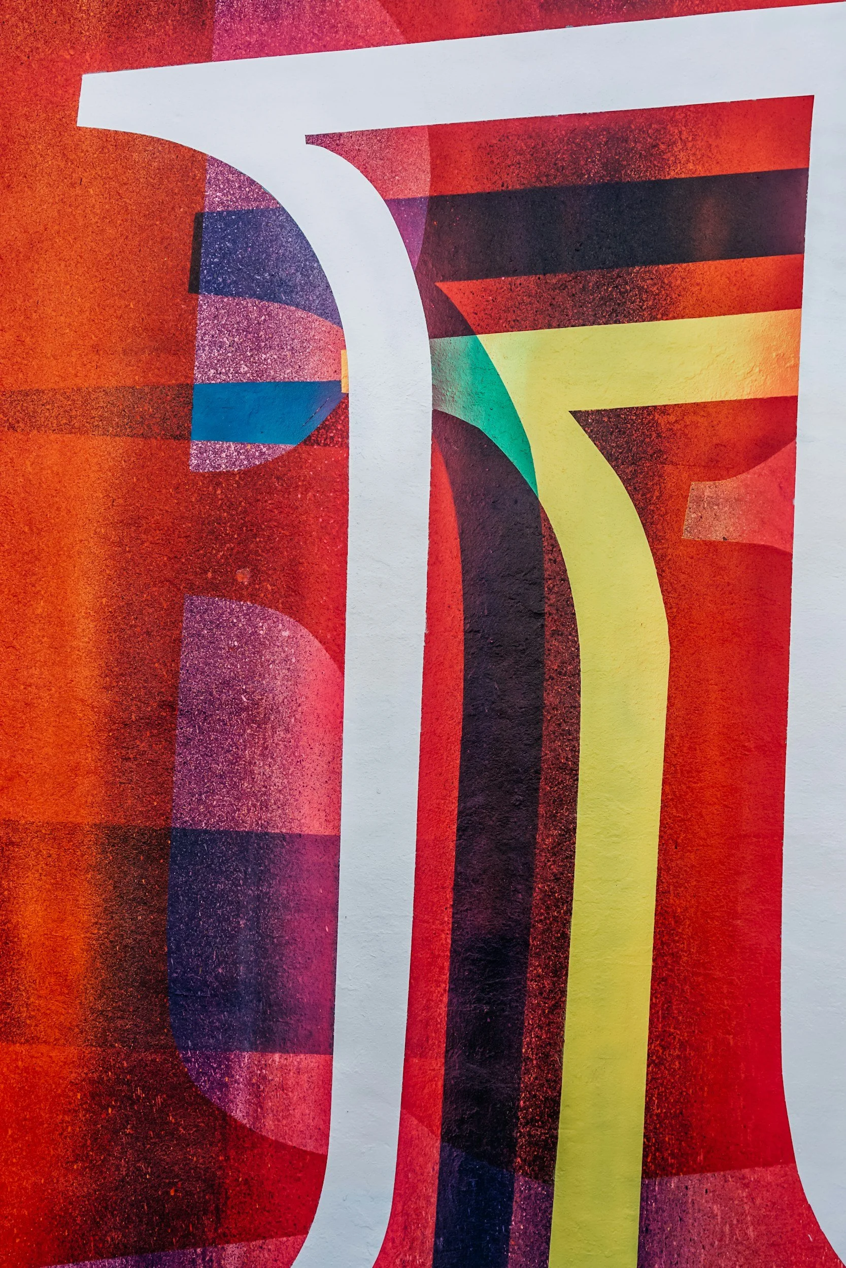 Close-up of a colorful abstract painting with various shapes and bold colors, including red, yellow, black, and teal.