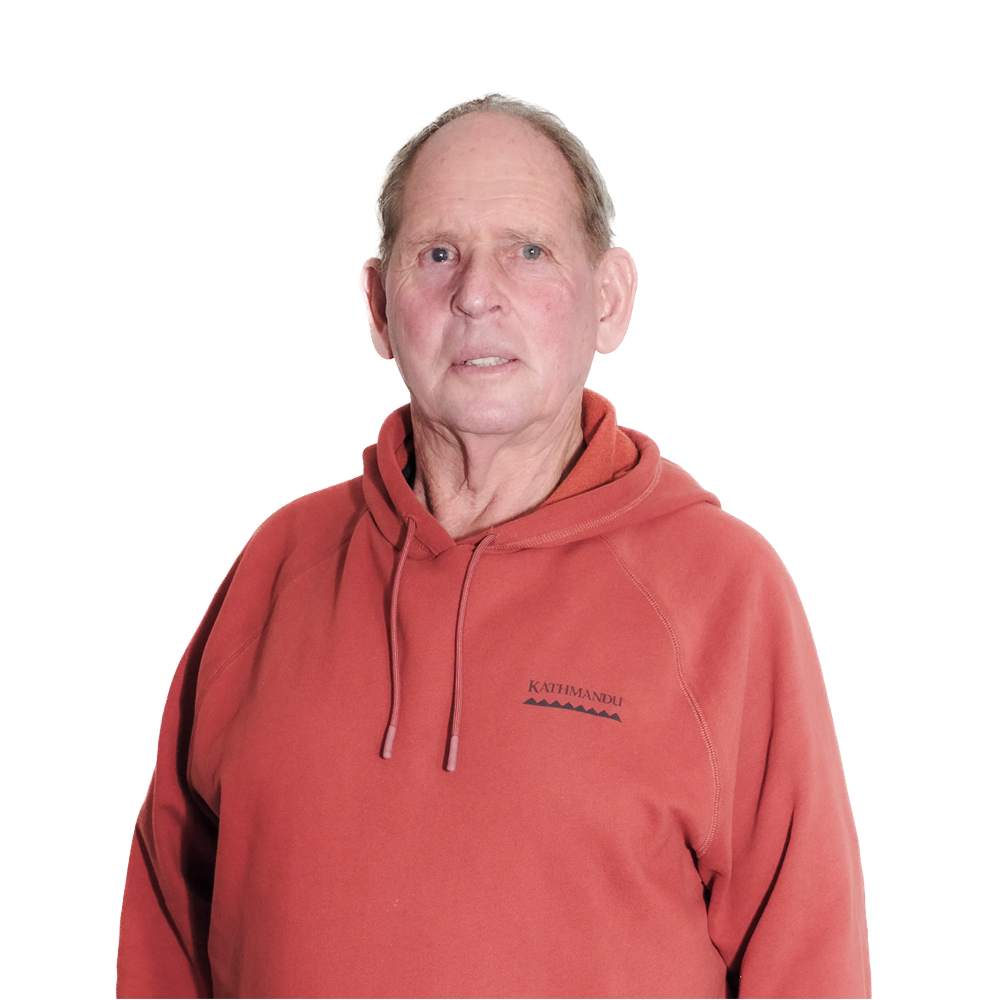 An elderly man with short light hair wearing a red hoodie with 'Kathmandu' logo standing against a transparent background.