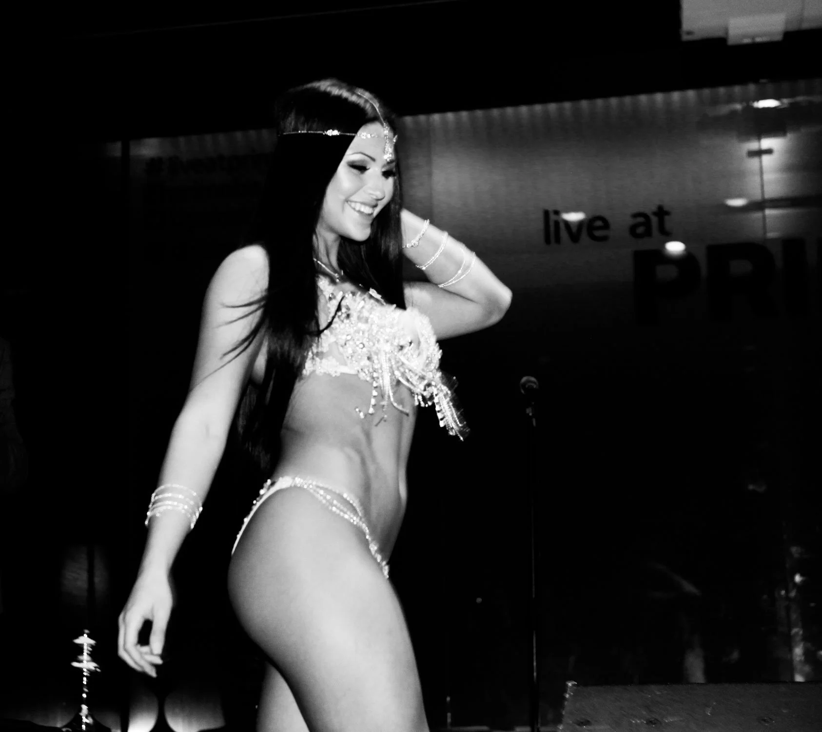 A woman with long dark hair smiling and posing on stage, wearing a SambaCouture custom bikini