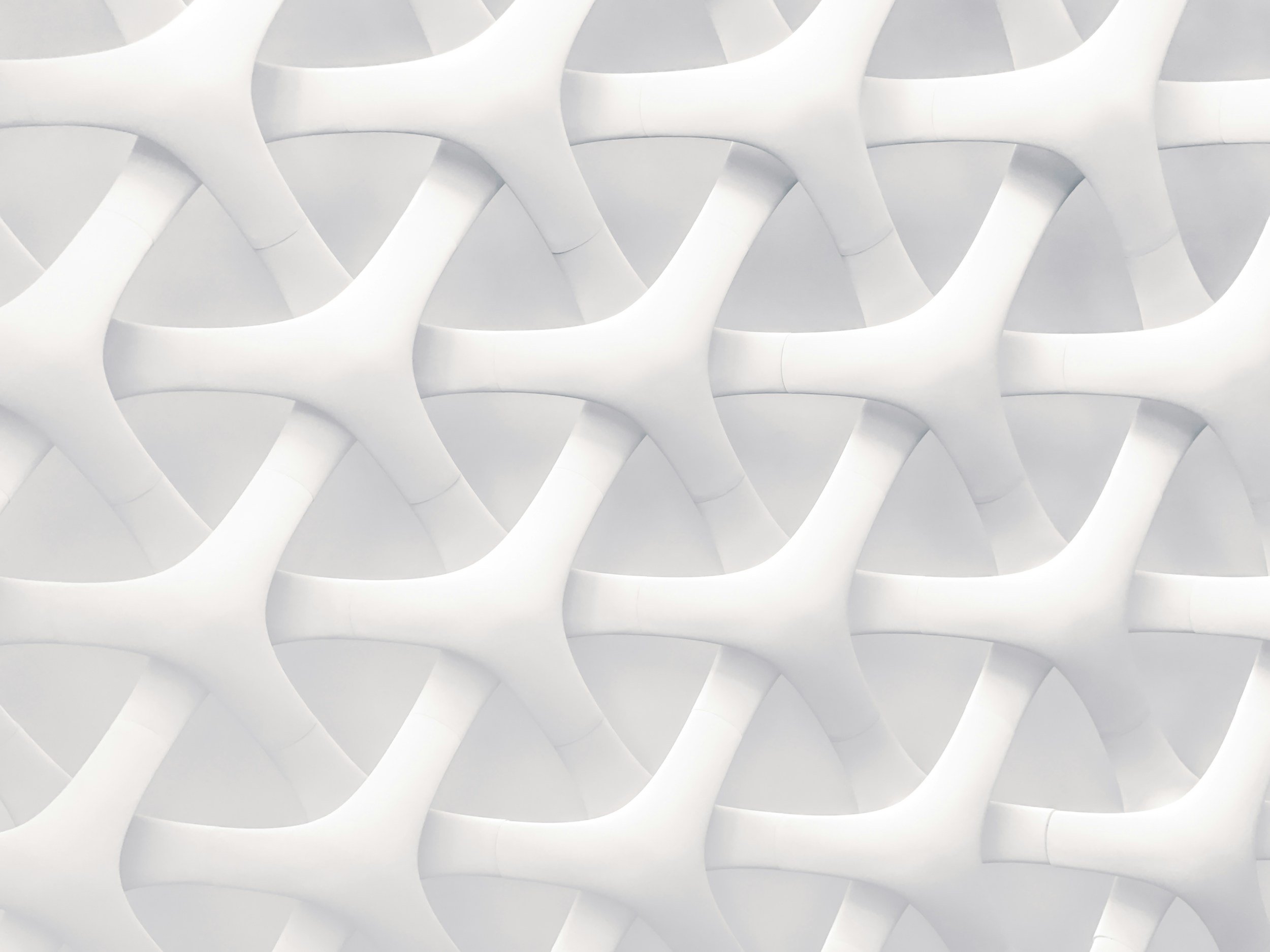Close-up view of an abstract architectural structure made of interconnected white curved beams forming a repeating pattern.