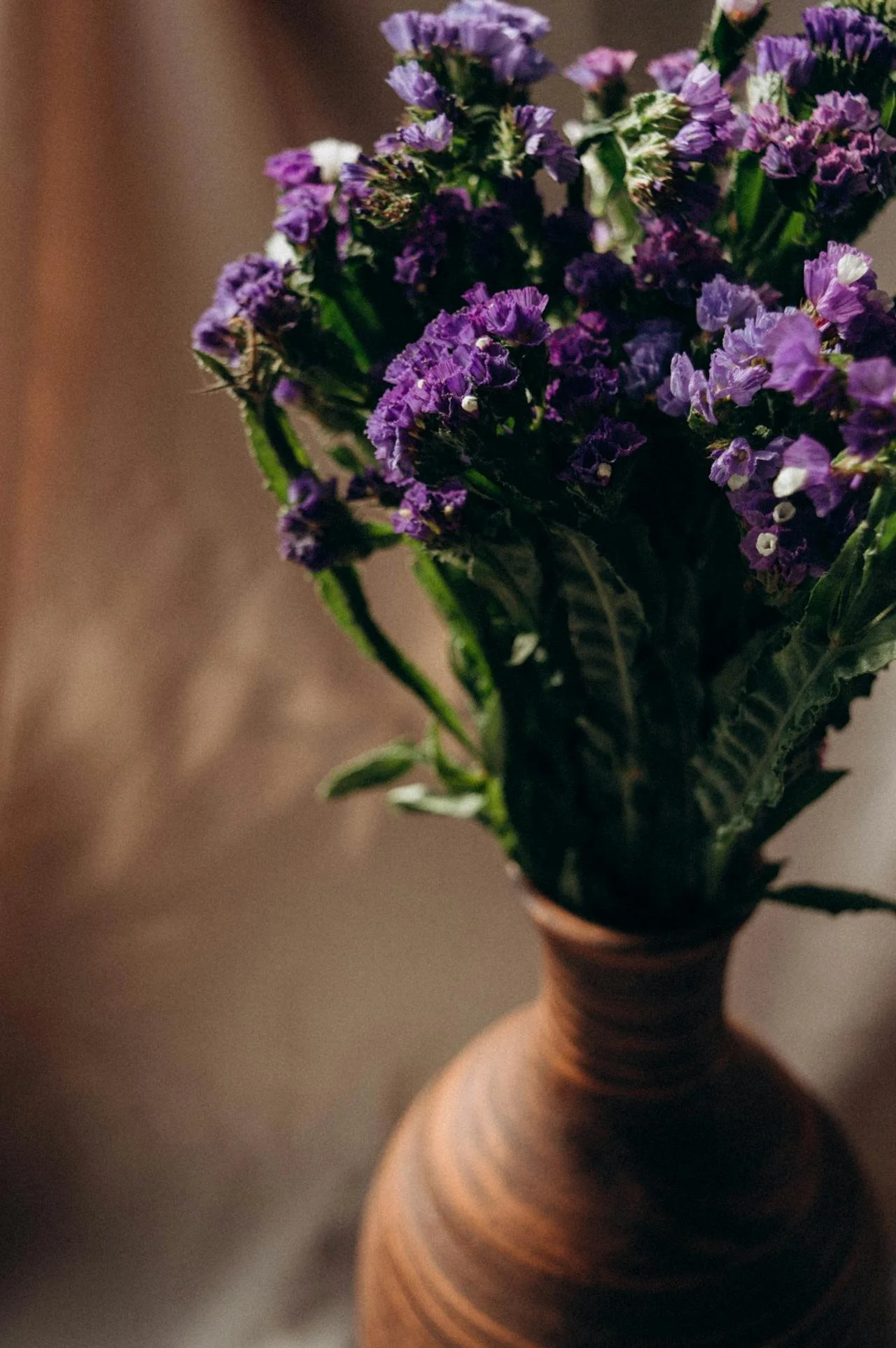 Purple flowers in a brown vase.
