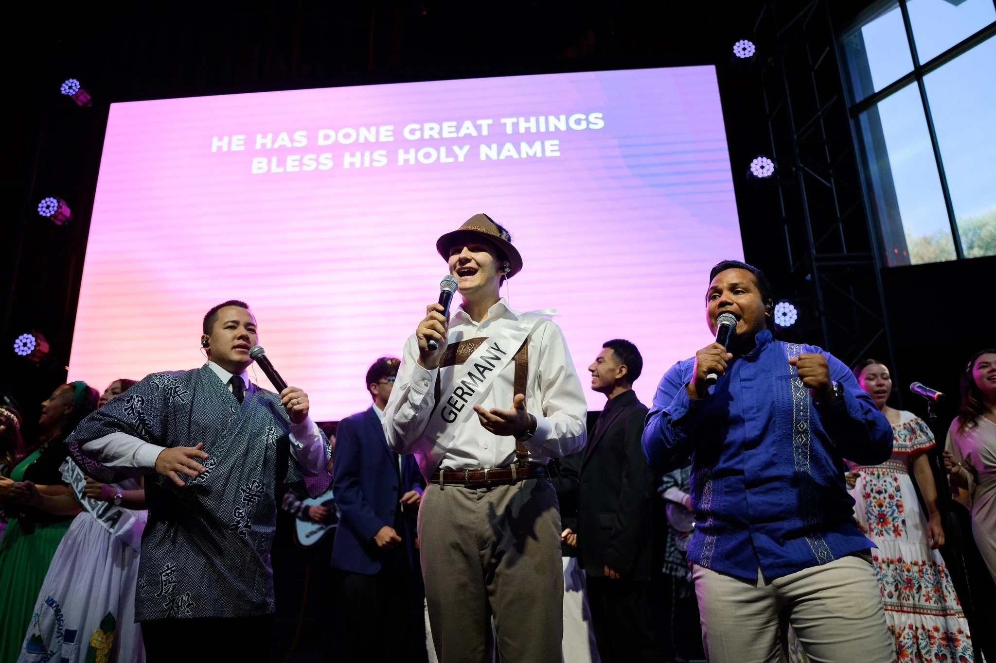 Three men sing together on the altar during worship at a Sunday service at International Pentecostal Church