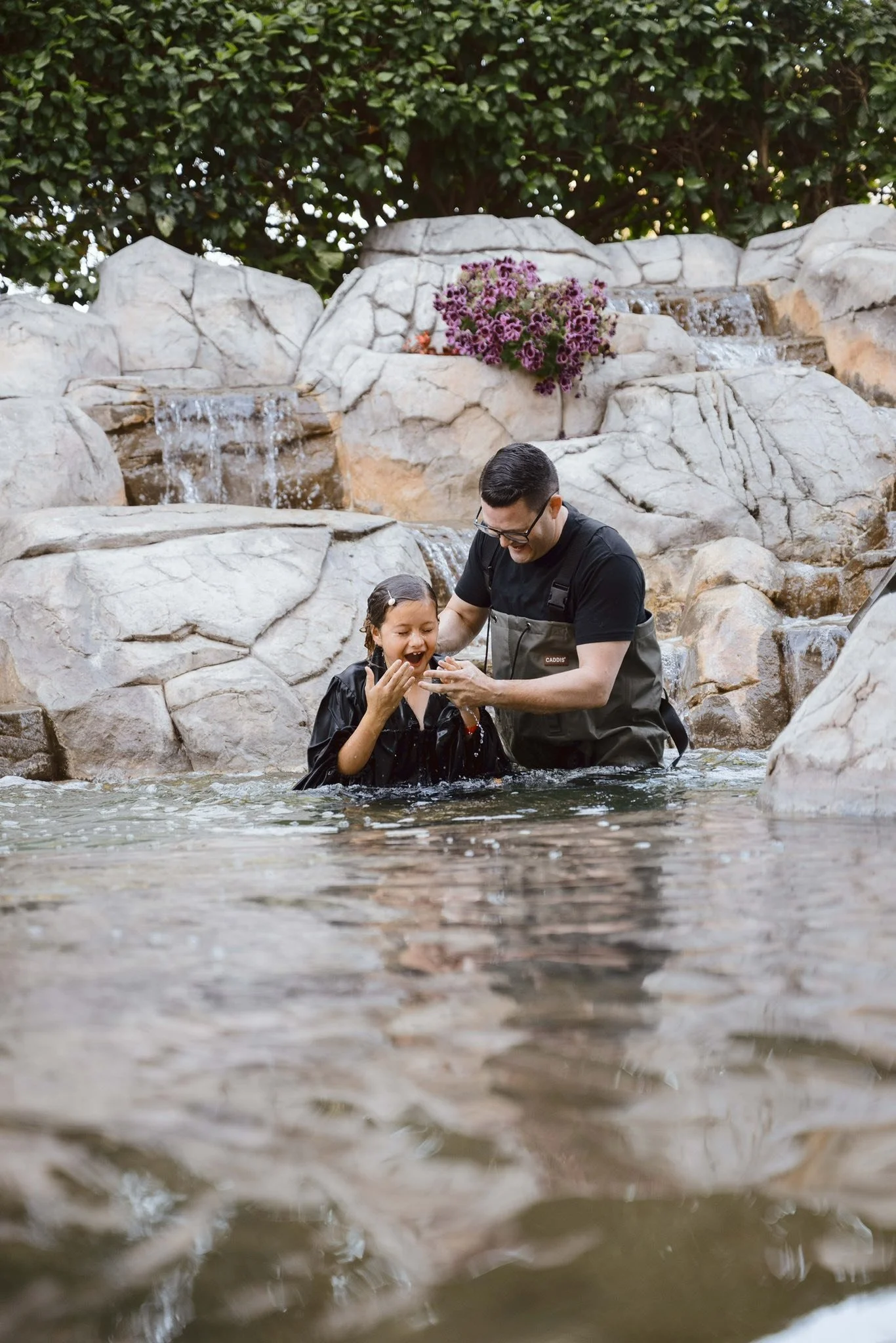 Pastor Dane Butler baptizes a young girl in a water pond at International Pentecostal Church