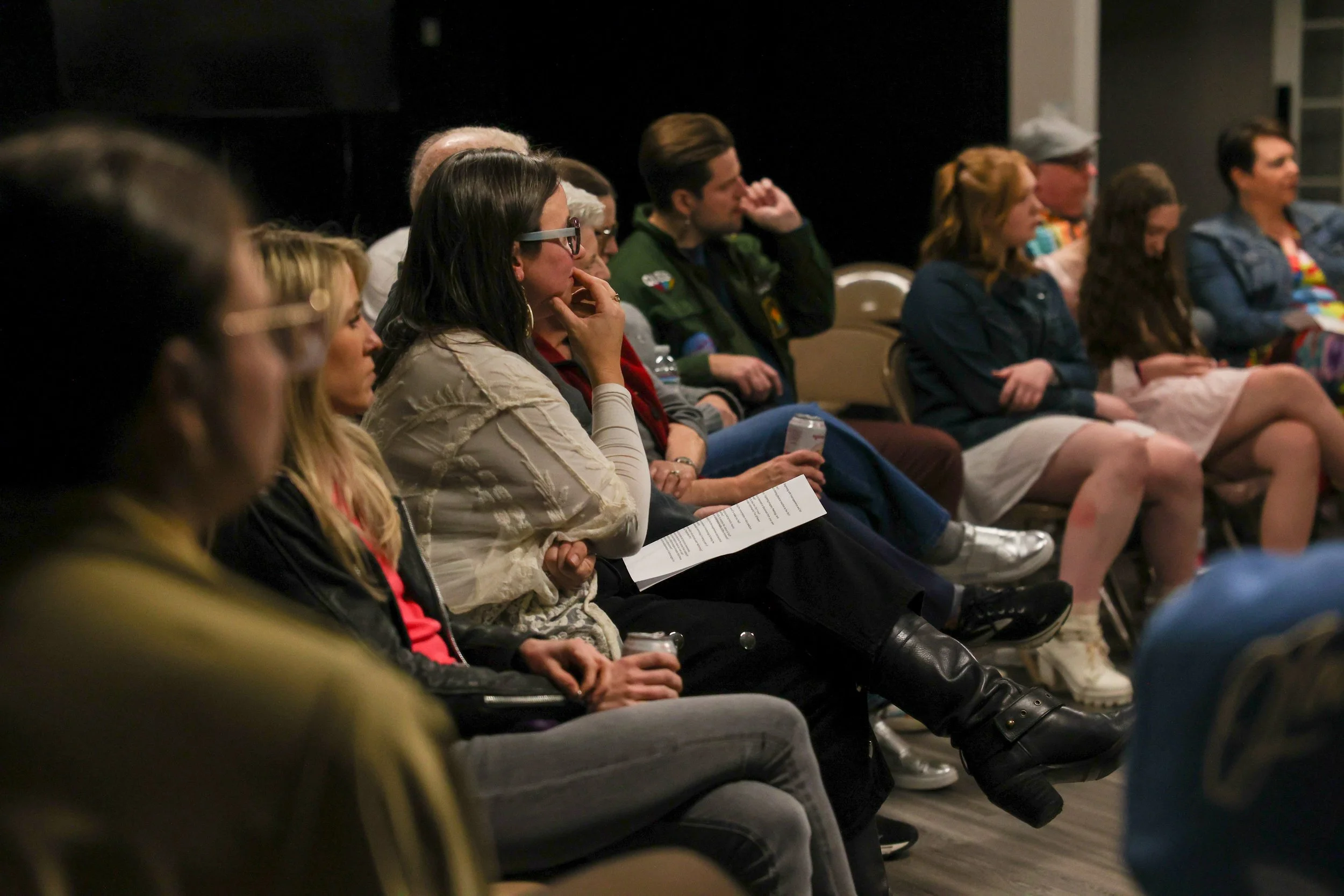 People sitting in chairs in a circle attending a community screening of Mr Jeses, some holding papers or drinks, focused and listening attentively.