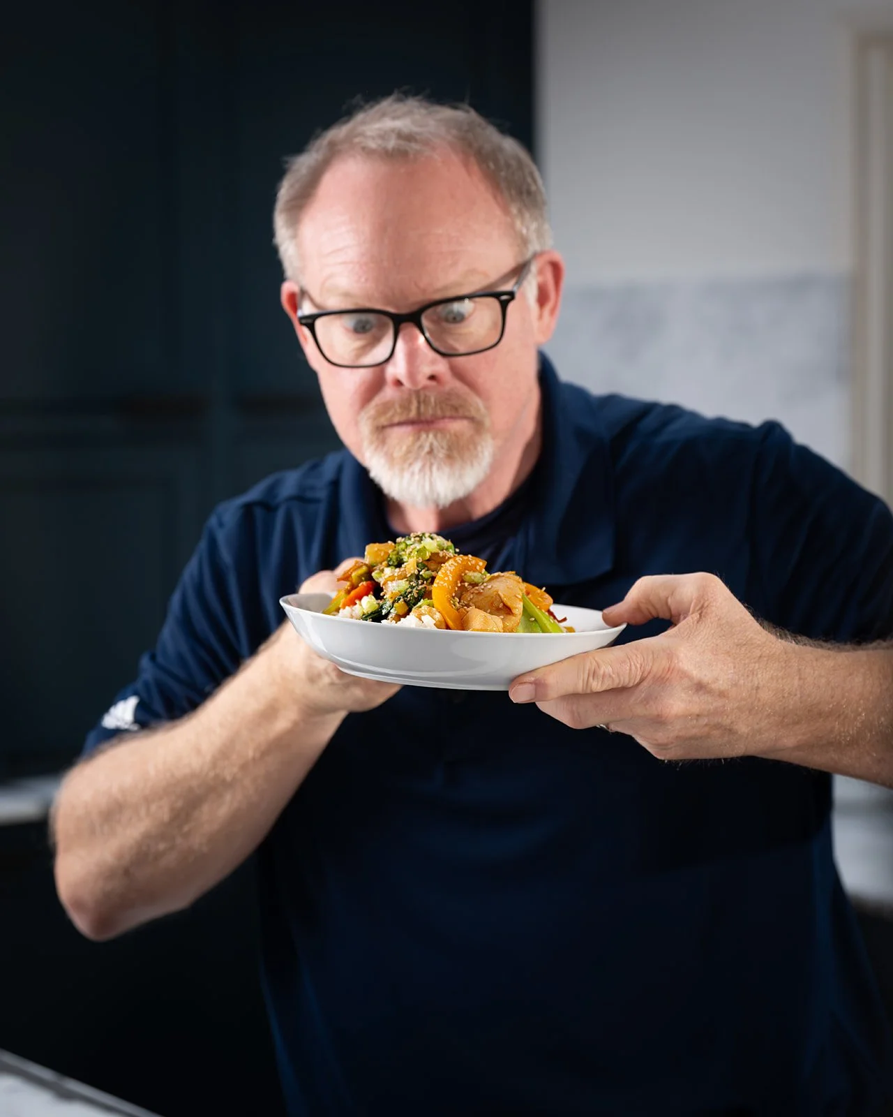silly man looking cross-eyed at bowl of colorful stir fried veggies and chicken over rice
