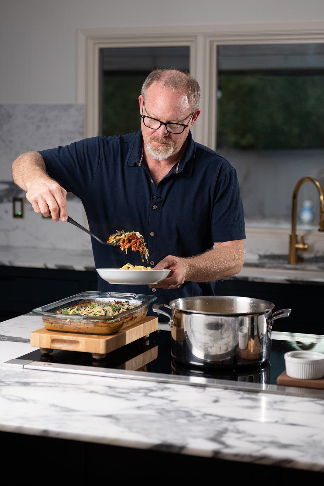 Matthew loading a plate with Chicken in sun-dried tomato cream sauce