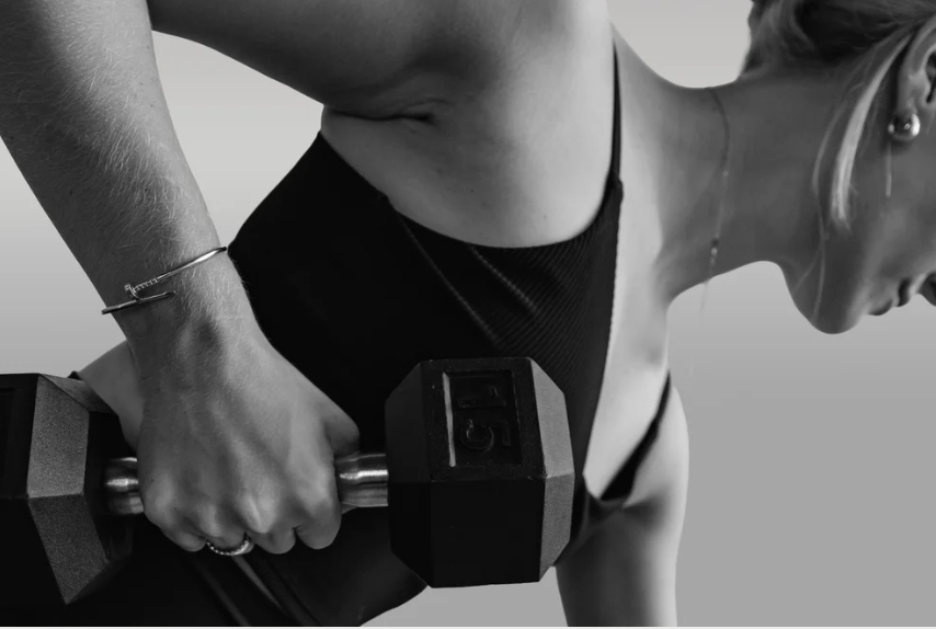 A woman performing a bent-over dumbbell row exercise, wearing a black sports top.