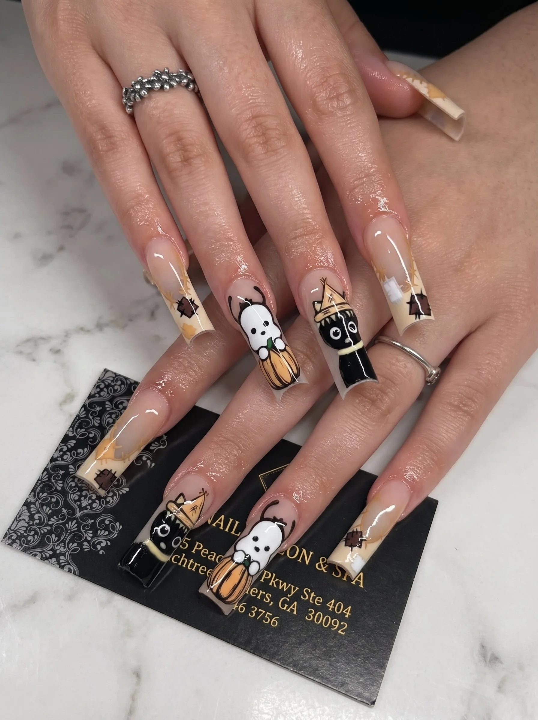Long coffin-shaped Halloween nail art featuring cartoon ghosts, witches, pumpkins, stars, and stitched black-and-white designs.