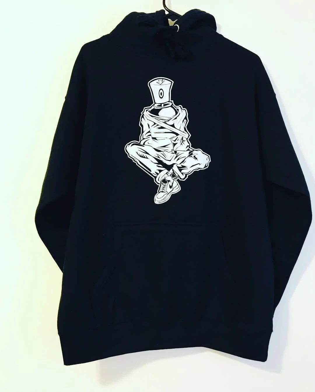 Black hoodie with a graphic of a character wearing a hoodie with a bottle for a head, sitting cross-legged.