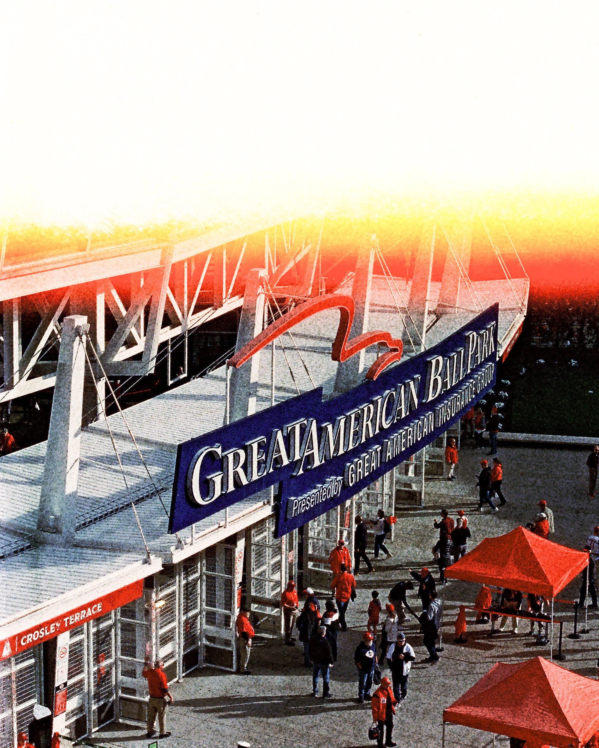 People walking outside of the Great American Ball Park stadium with a large sign and a red tent.