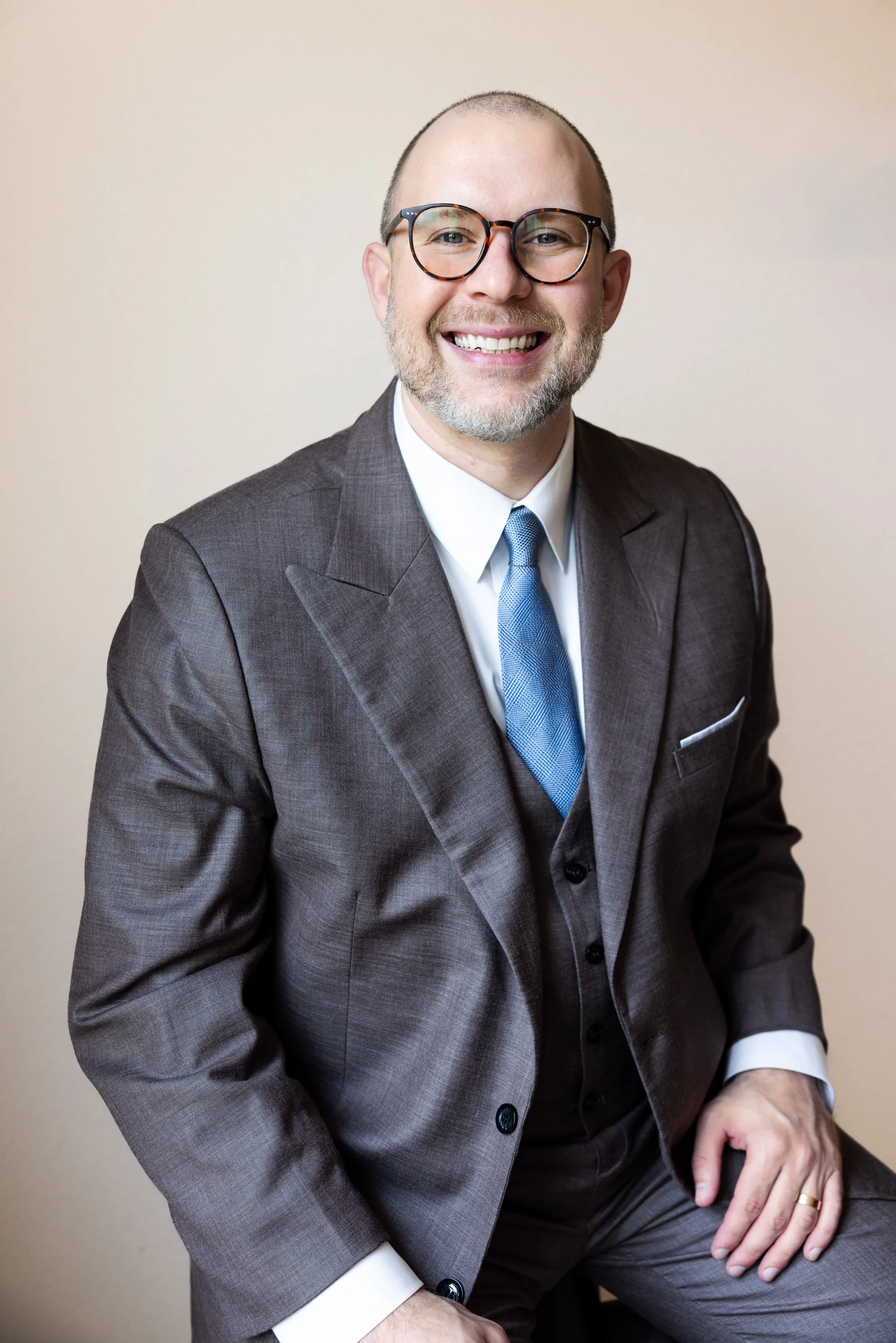 A portrait of founder and CIO Spence Almond wearing a charcoal grey suit and a light blue tie.