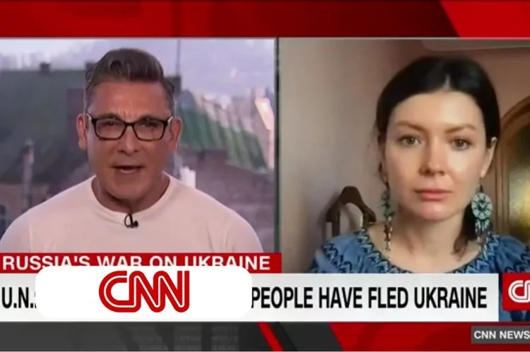 CNN news broadcast showing a split-screen interview about the Russia-Ukraine conflict; the left side features a male news anchor with glasses, and the right side shows a female interviewee with dark hair and blue earrings.