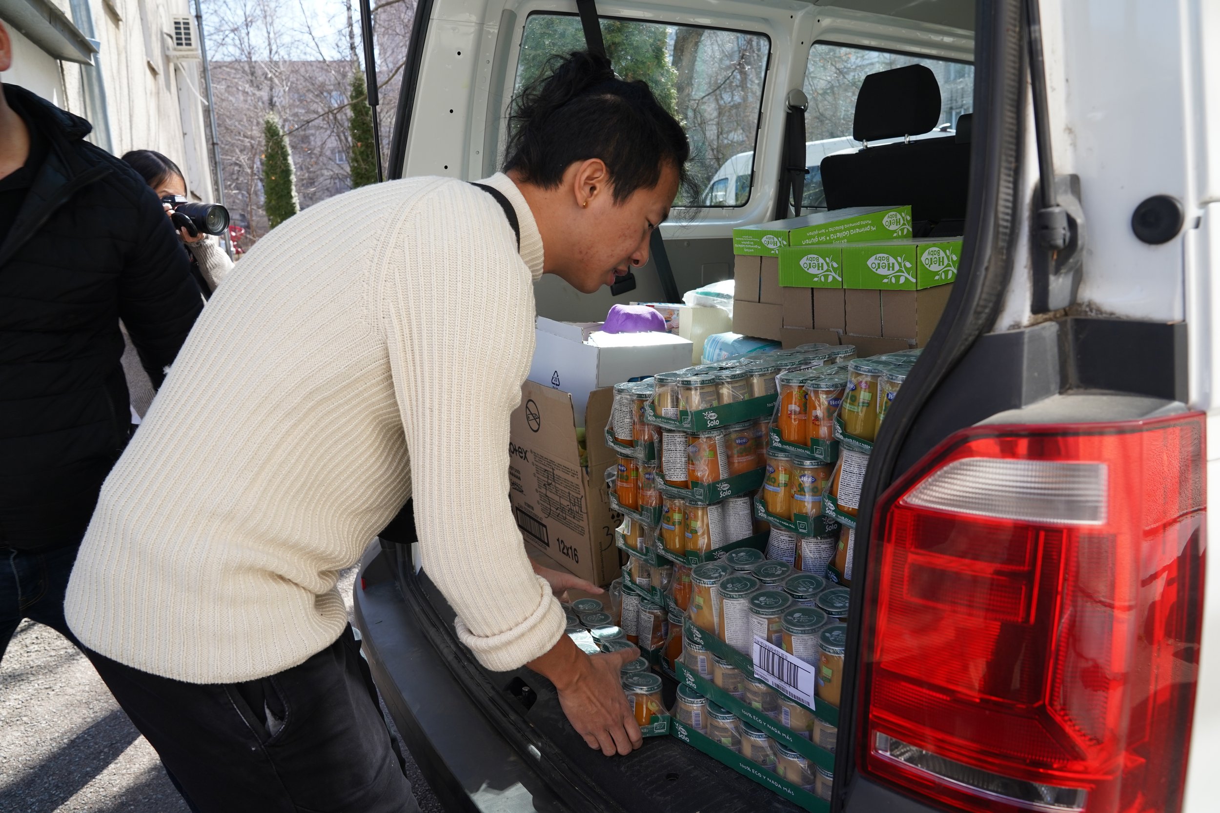 A person loading cans of food into the back of a vehicle during a food drive.