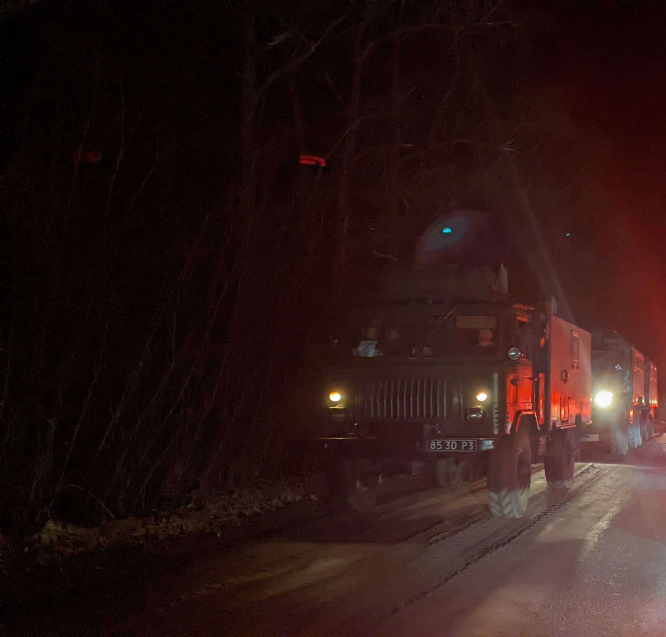 Fire trucks with flashing lights parked on a dark rural road at night.