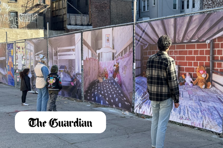 People viewing a large outdoor mural of a child's bedroom featuring stuffed animals, pink walls, and a bed with a polka-dot blanket.